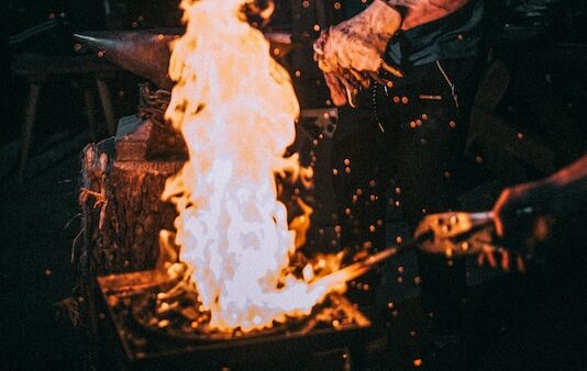 man standing beside flame during nighttime