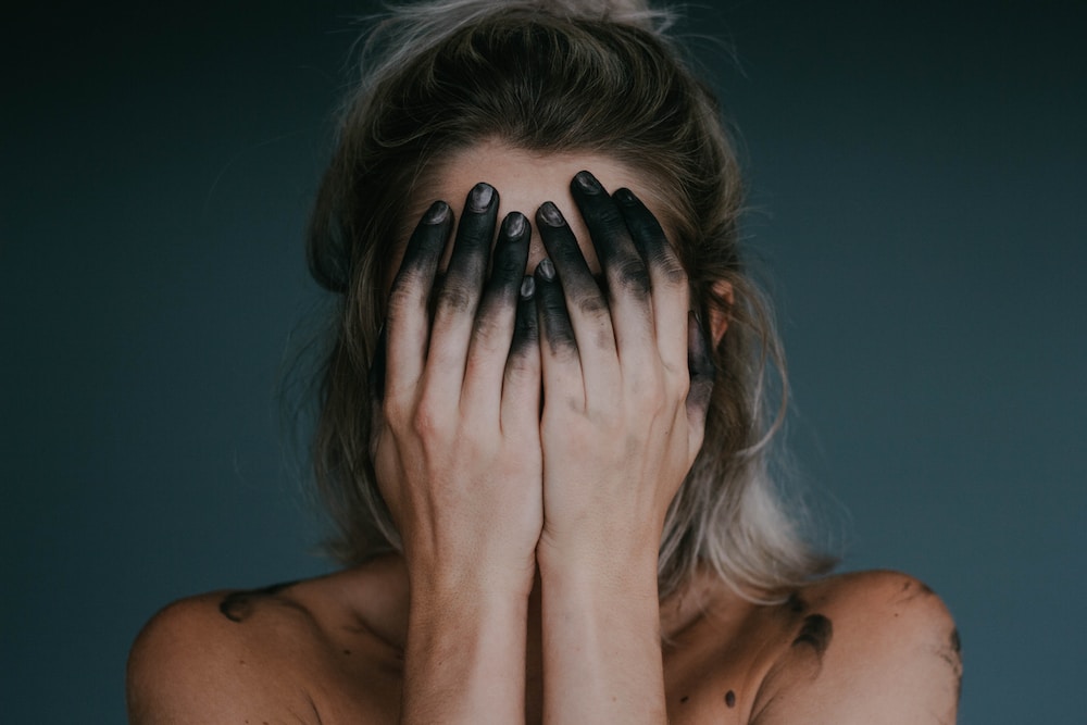 woman covering face with both hands closeup photography